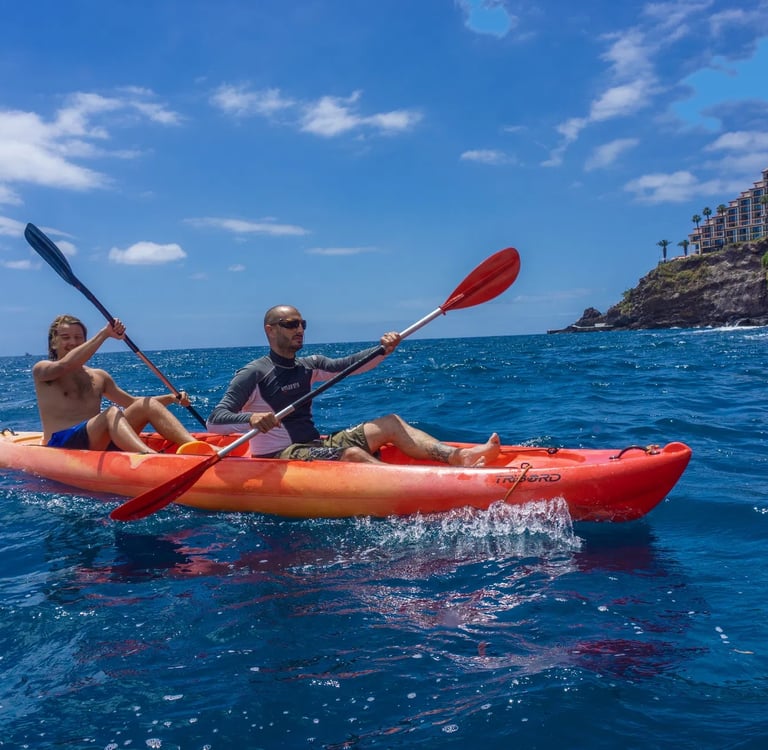 Tandem kayak on the deep blue Atlantic Ocean with the volcanic cliffs and hotel of Funchal in the background