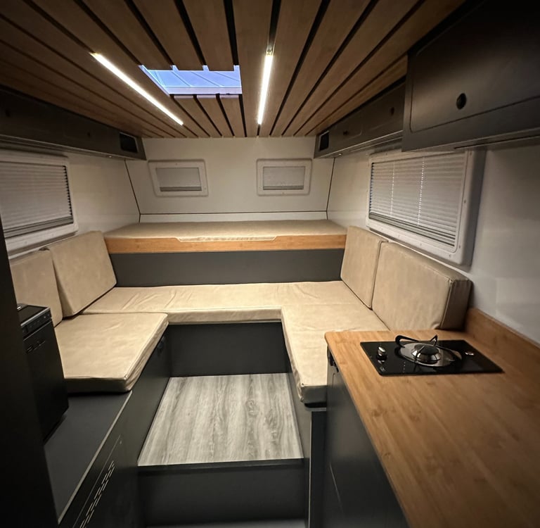 salón interior de una célula camper con luces led, cama y sofas