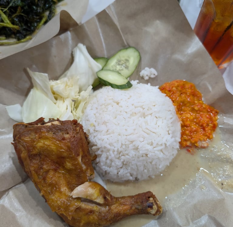 Malaysian ayam goreng fried chicken served with steamed rice, spicy sambal, and fresh vegetables.