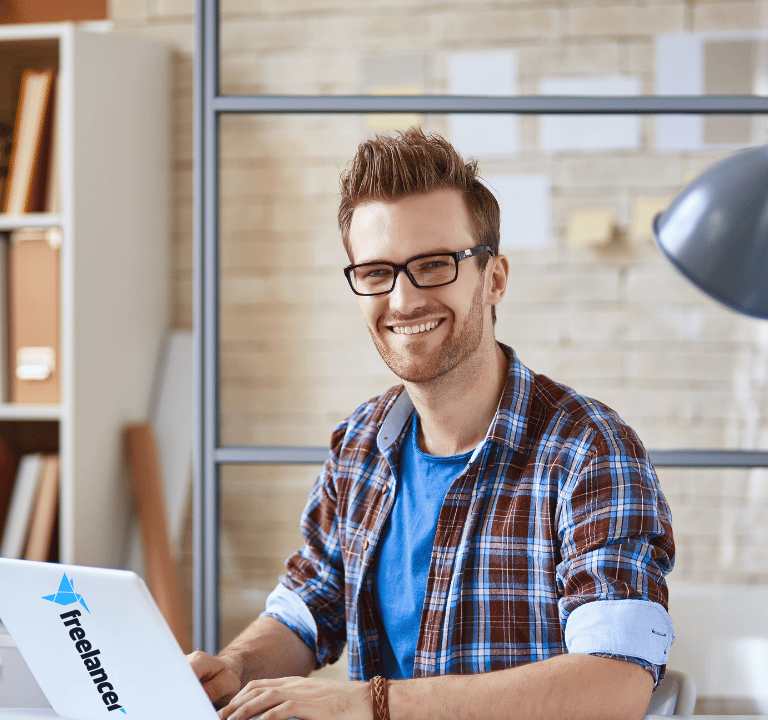 a man sitting at a desk with a laptop computer freelancing