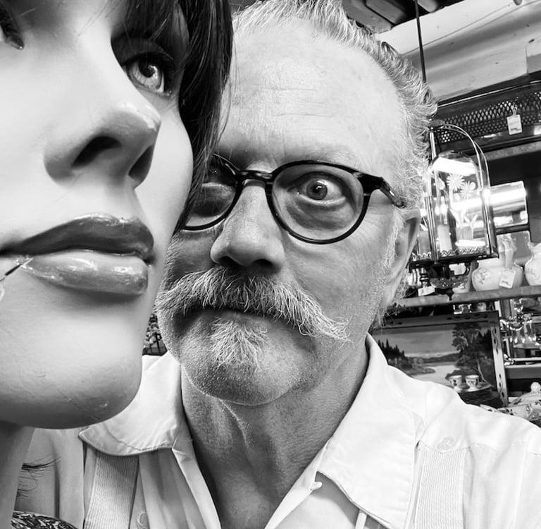 Dan Self, a man with a mustache and glasses looking at a mannequin