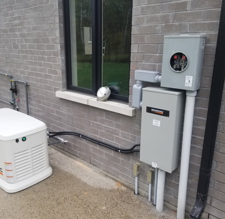 A white Generac standby home generator installed outside a grey brick house next to electrical boxes.