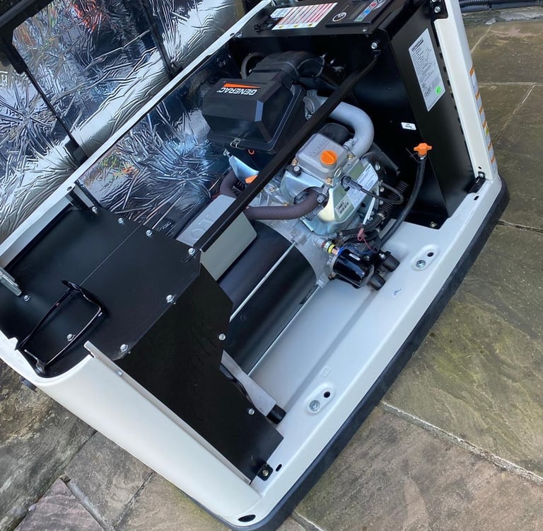 Internal engine components of an open Generac home standby generator installed on a stone patio.