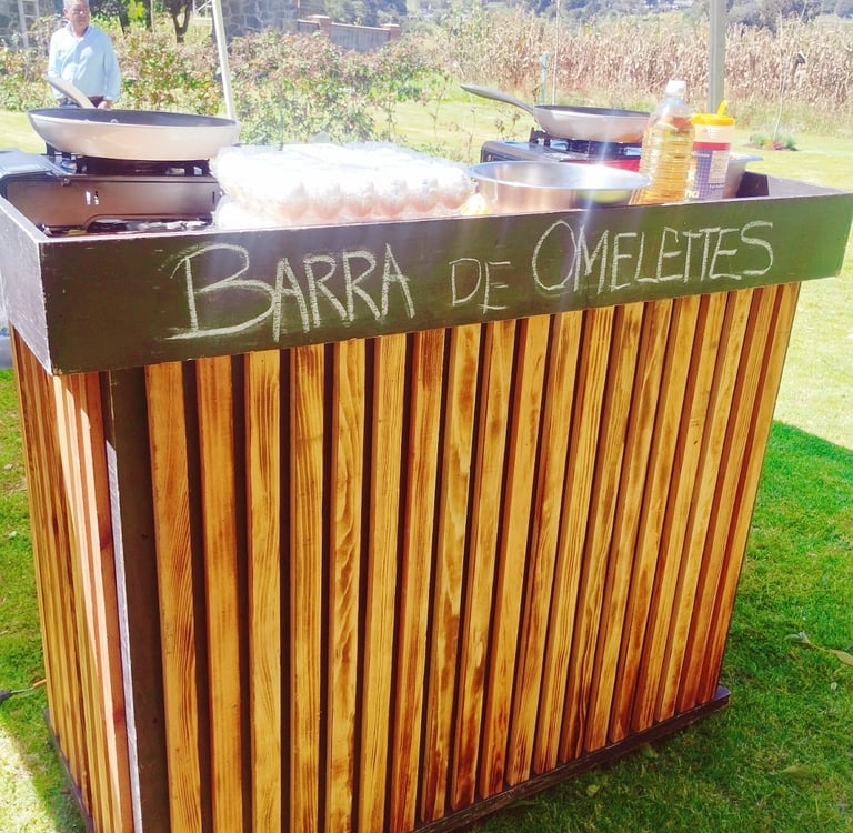 Outdoor wooden omelette bar station with fresh eggs and frying pans for event catering.