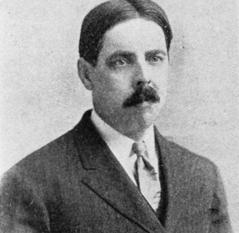 um homem de terno e gravata com bigode