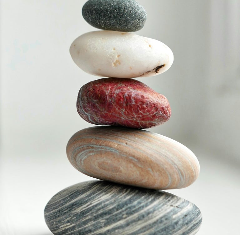 A balanced stack of five smooth river stones in various colors representing zen and stability.