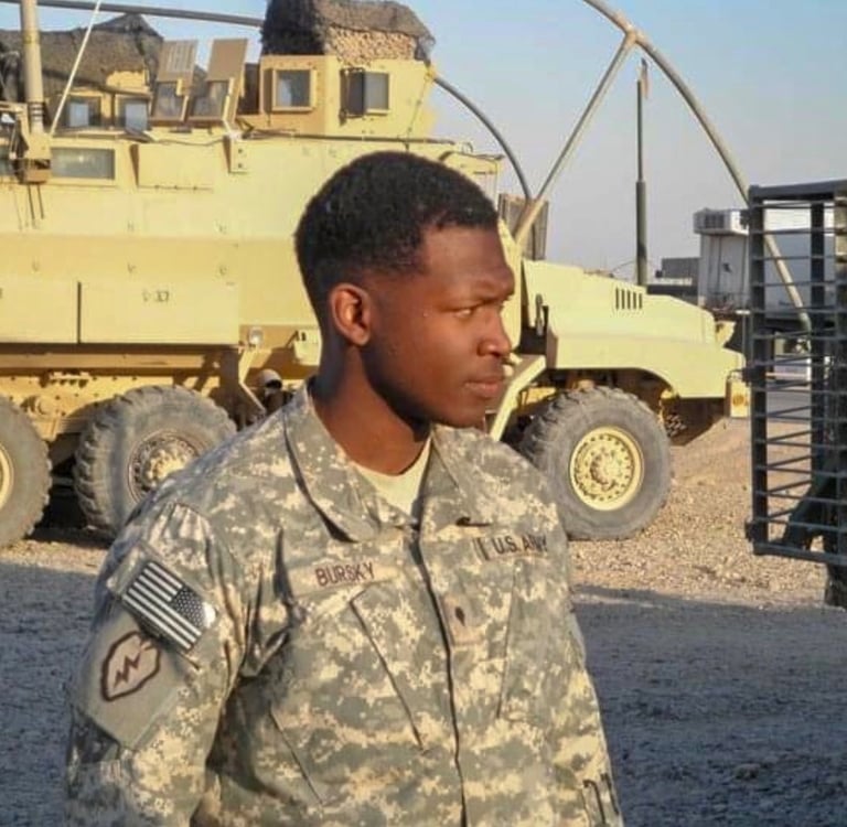a soldier in uniform standing in front of a military vehicle