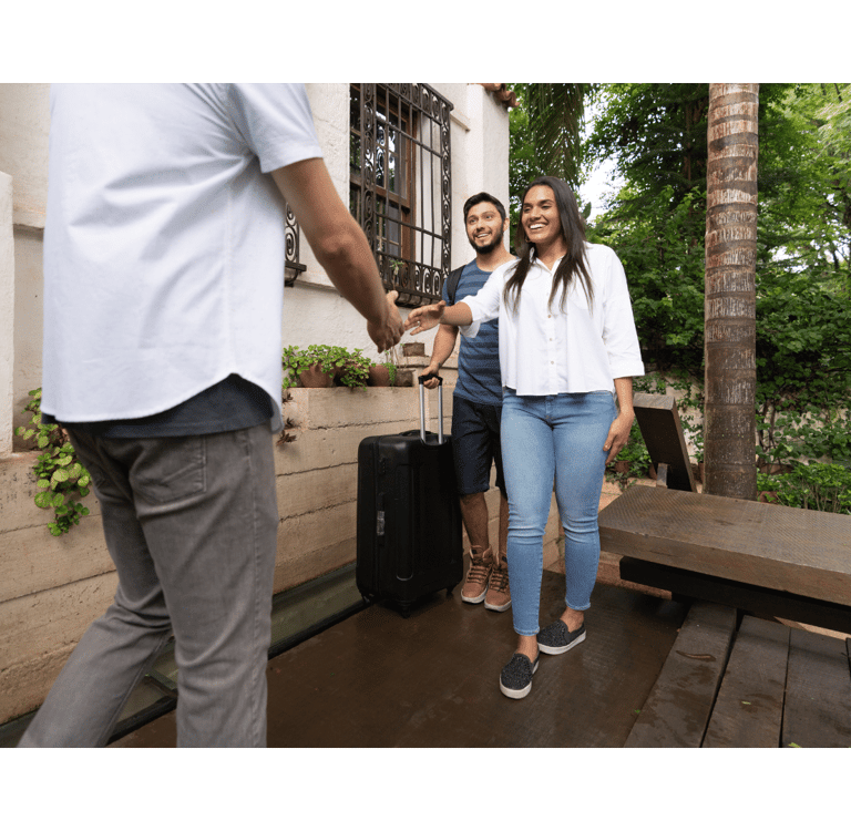 a man and woman shaking hands in front of a house