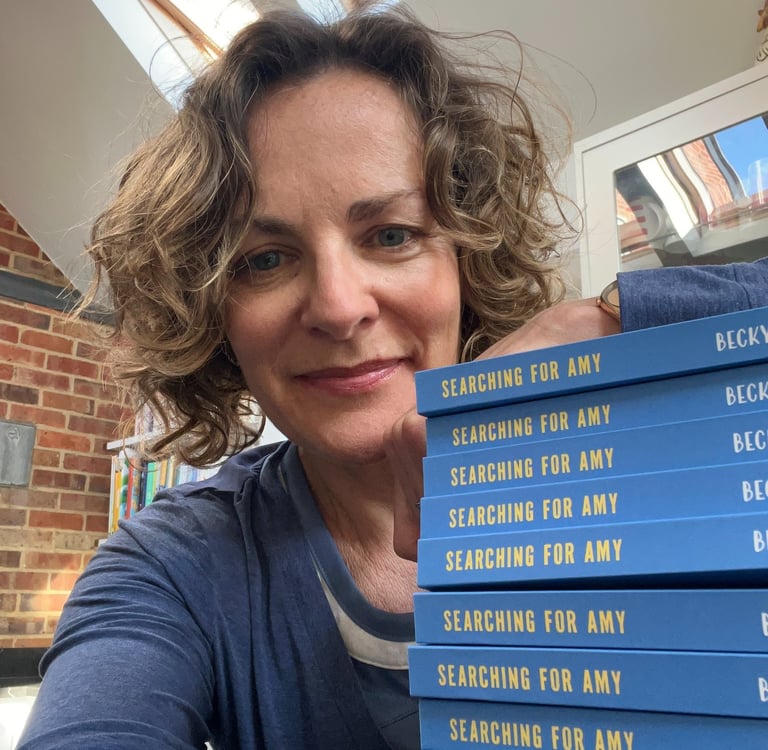 author with a pile of copies of Searching for Amy