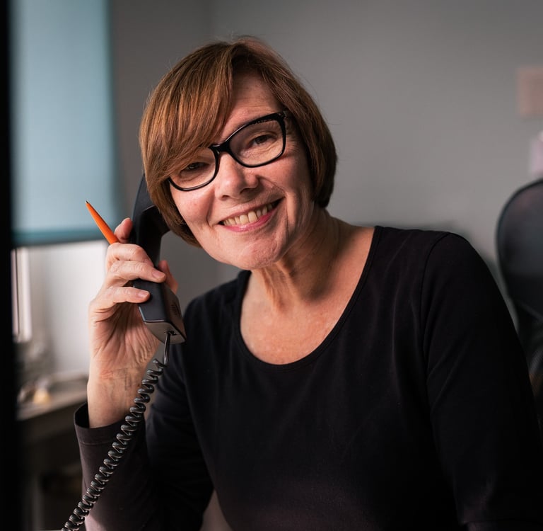 eine frau mit braunen haaren und brille spricht in ein telfon im atelier rohlfs