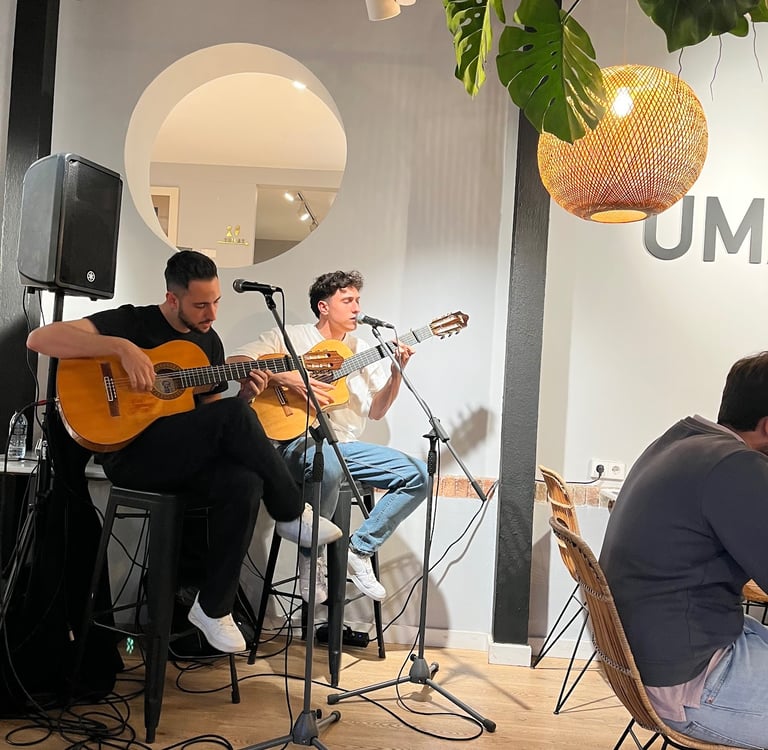 Two young musicians playing acoustic guitars and singing live at a cozy cafe with modern decor.