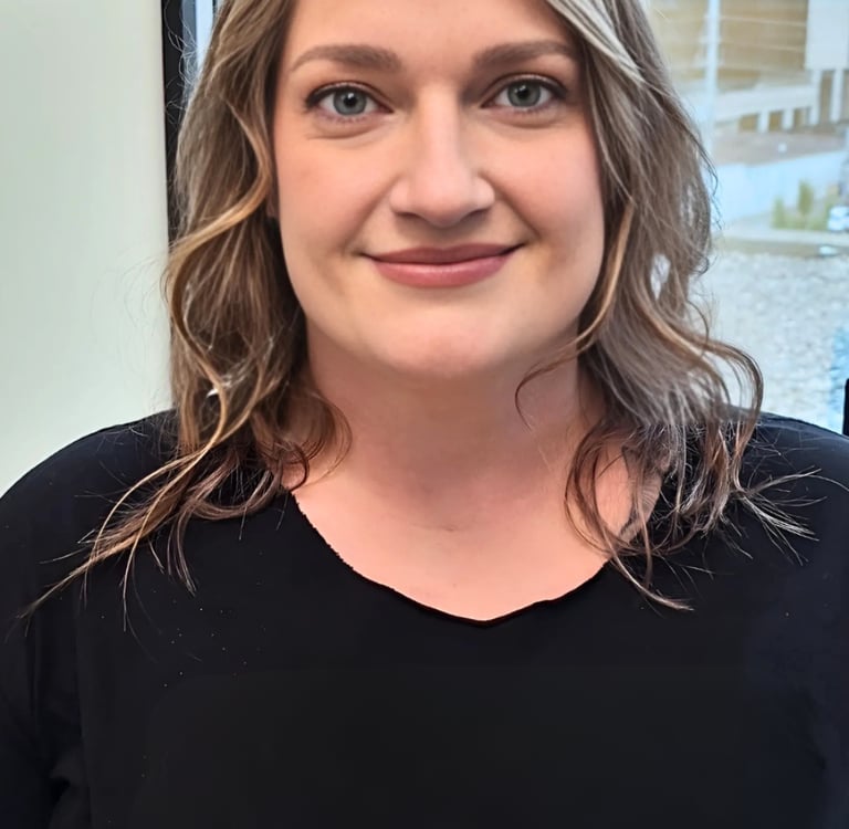 Professional portrait of a smiling woman with wavy blonde hair wearing a black shirt.