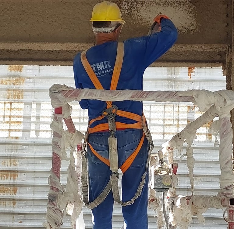 Homem Aplicando Argamassa Contra Fogo em Estrutura Metálica