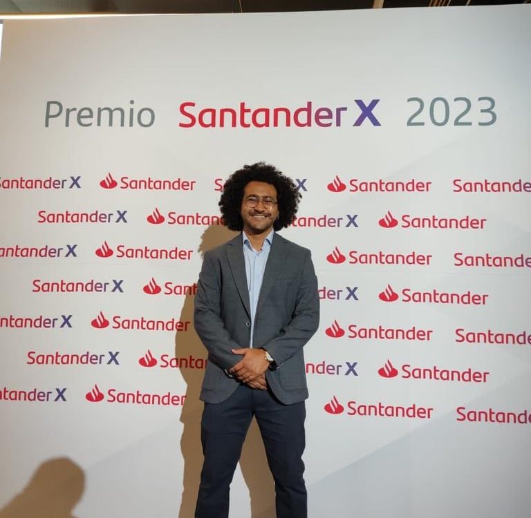 a man in a suit and tie standing in front of a sign that says,