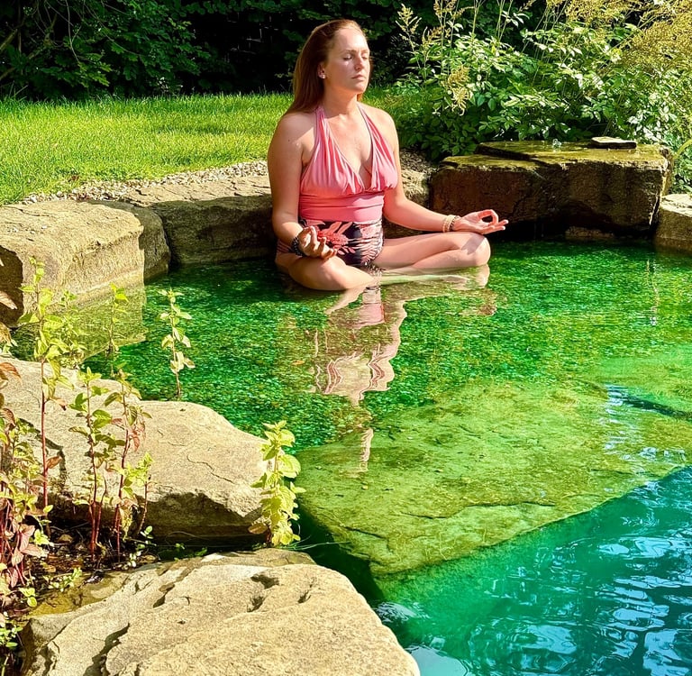 A picture of Alena Booth meditating in a natural lake in UK