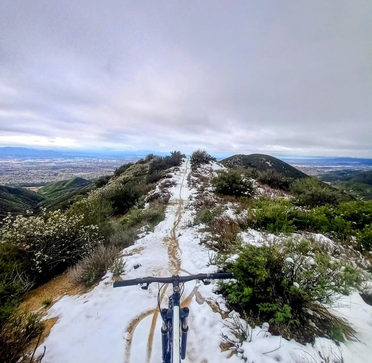Mountain bike POV riding snowy trail in Southern California with city views below