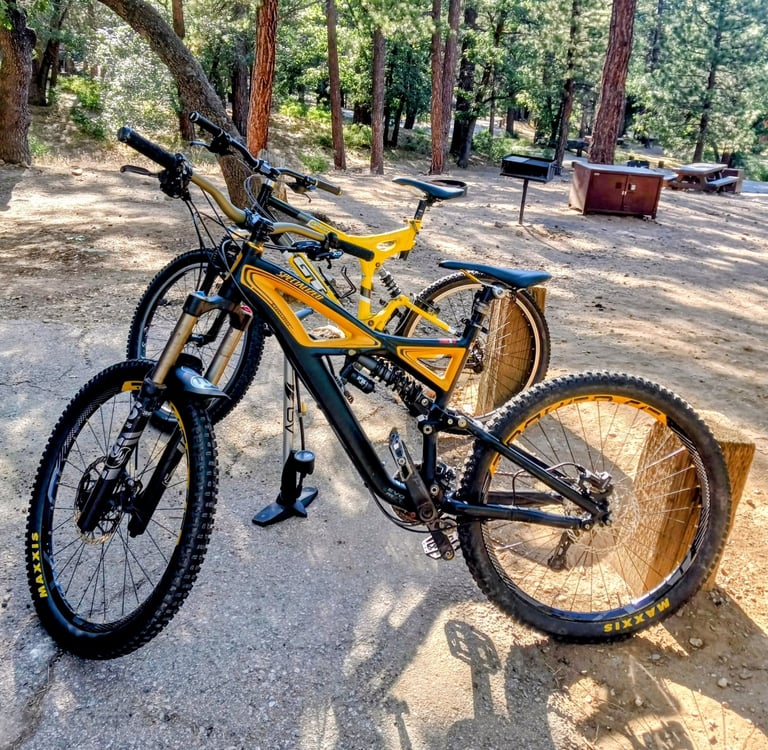 Two mountain bikes side by side on a trail showing handlebar width comparison