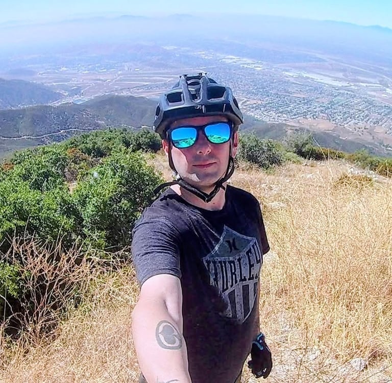 mountain biker on top of foothills wearing sunglasses and helmet