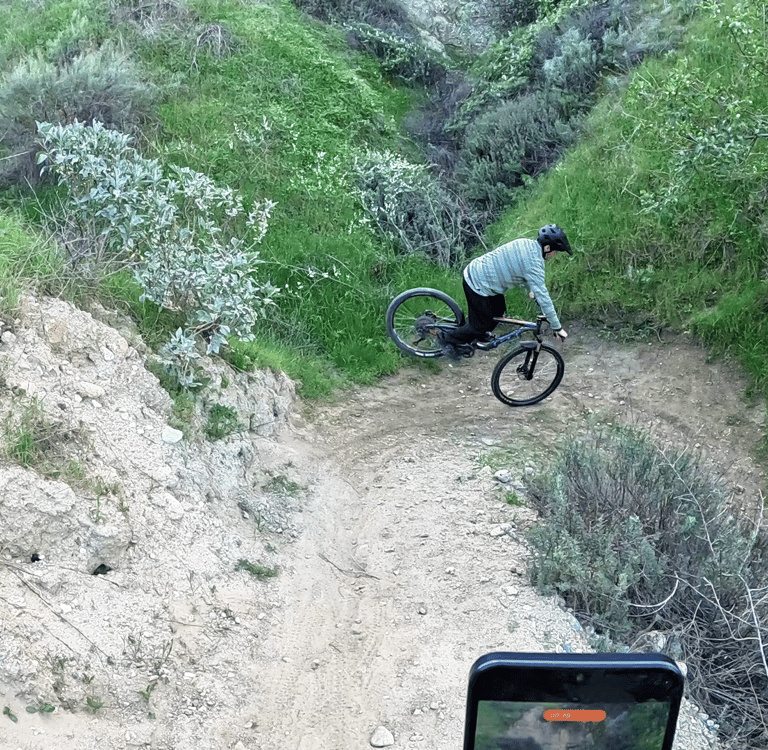 Mountain biker rotating shoulders to pivot rear wheel around a tight switchback using a stoppie tech
