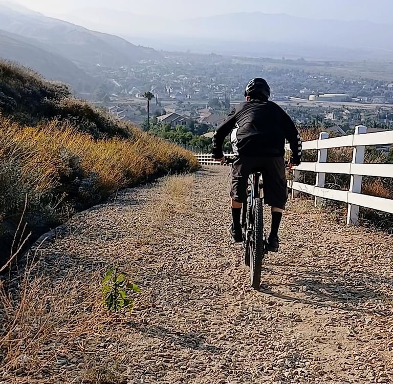 Mountain biker riding downhill on a loose gravel trail, focused on balance and control.