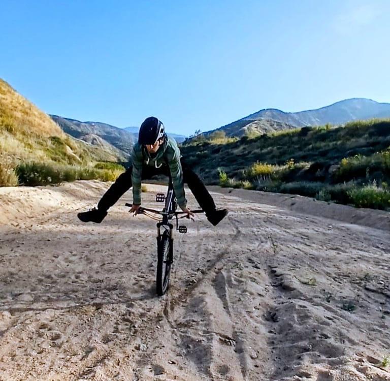 Mark Hower in a controlled bail going over the handlebars on a mountain bike on a sandy Southern Cal
