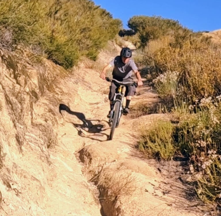MTB rider navigating a deep rutted dirt trail section in dry Southern California terrain