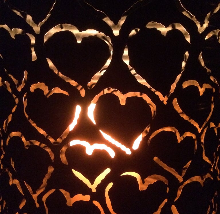 Warmes Kerzenlicht scheint durch Metallherzen und symbolisiert Wärme und Verbindung.