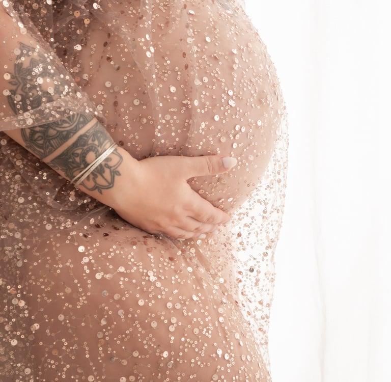 Maternity photoshoot featuring a pregnant woman with tattoos in a rose gold sequin gown.
