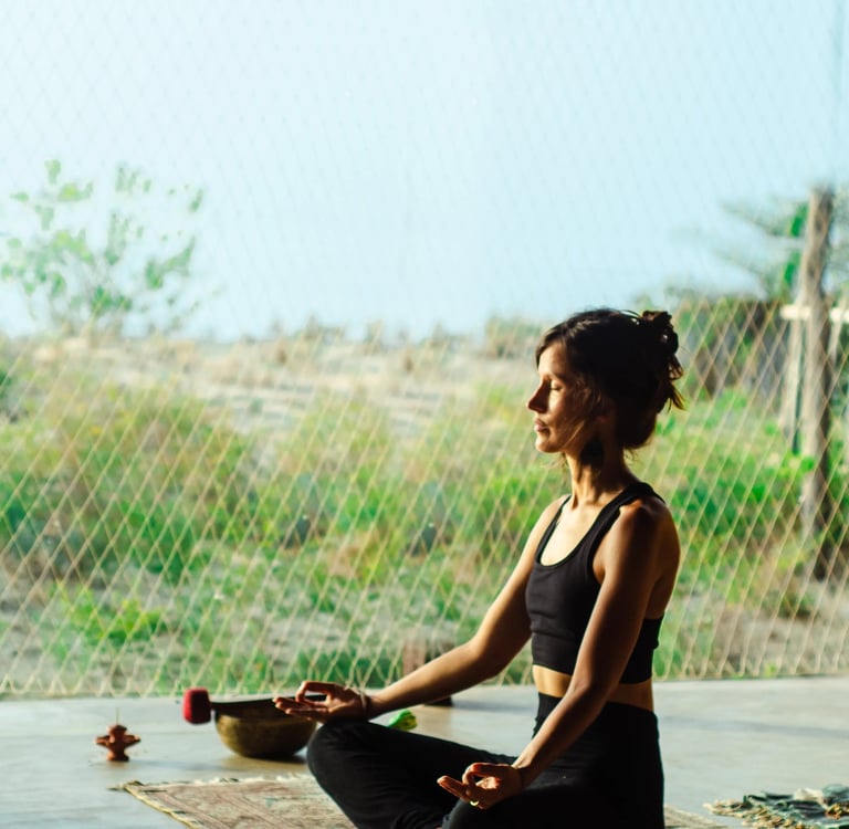 Isabel Maass meditating in yoga shala with afternoon sun, symbolizing demystifying meditation and mindful presence.