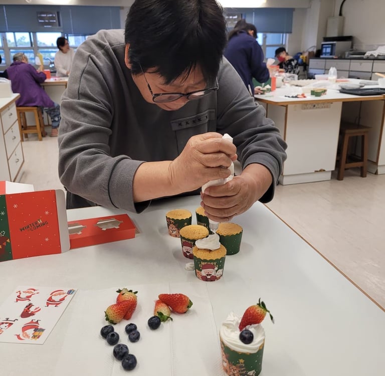 「社福機構長者烘焙班：長者專注練習聖誕 Cupcake 唧花裝飾，透過手作活動訓練手部肌肉並建立自信。」
