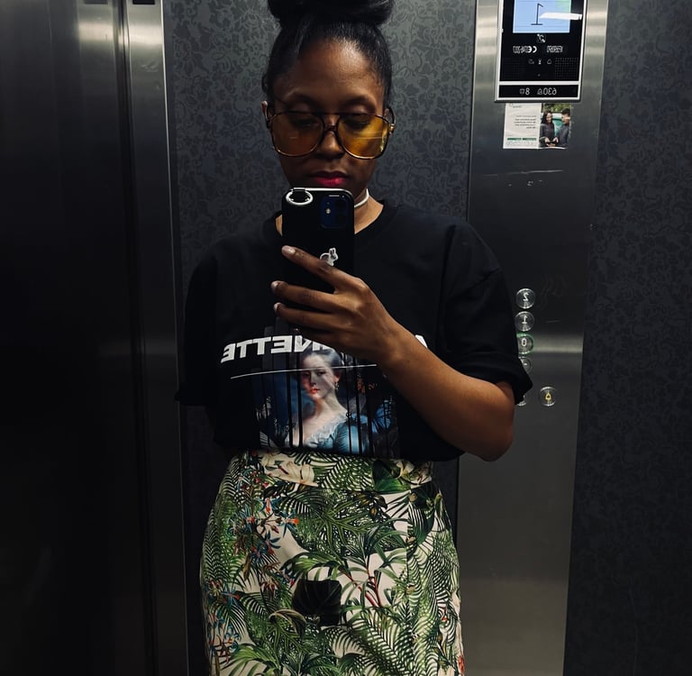 a woman in a black shirt and skirt with a phone