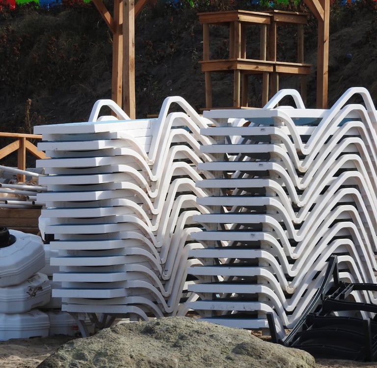 a pile of plastic chaise lounges chairs with plastic chairs