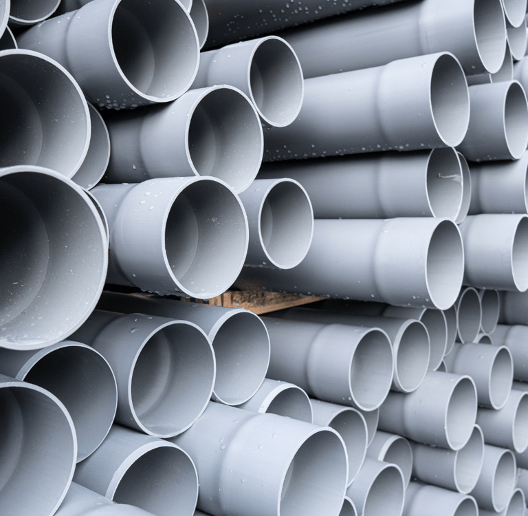 a stack of plastic pipes and pipes in a pile