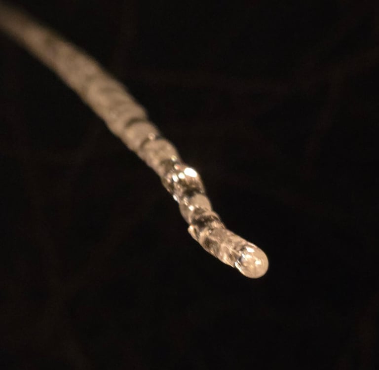 a long drip of icicle against a black background