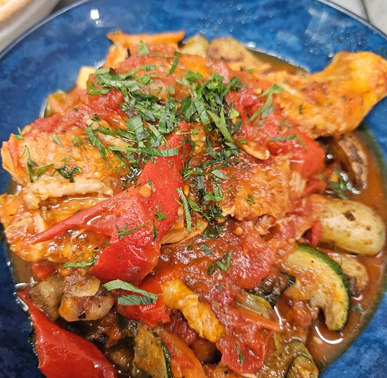 Cacciatore au poulet cuit lentement avec des poivrons rouges, des courgettes et de la sauce tomate.