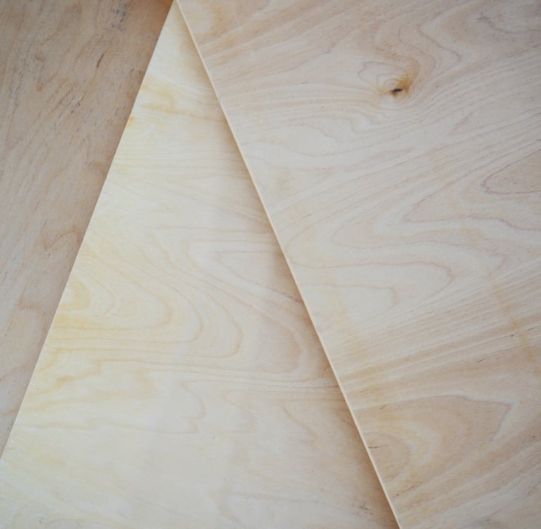 Close-up of stacked sheets of high-quality birch plywood showing wood grain and layered edges.