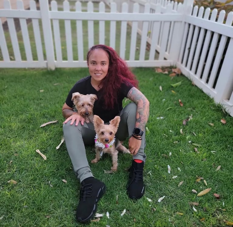a woman sitting on the grass with two dogs