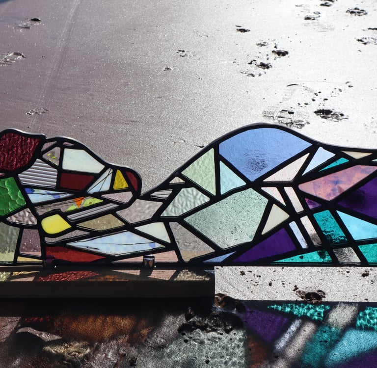 Full Sized Stained Glass Woman. Photograph is taken on a beach at low tide. Art work by Laura Kriefman