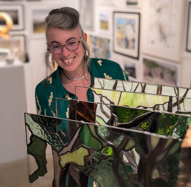 Image of Artist Laura Kriefman at Biennale Exhibition opening. Laura is smiling and looking at her bespoke glass art