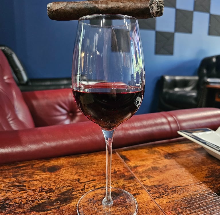 cigar resting on top of wine glass filled with red wine