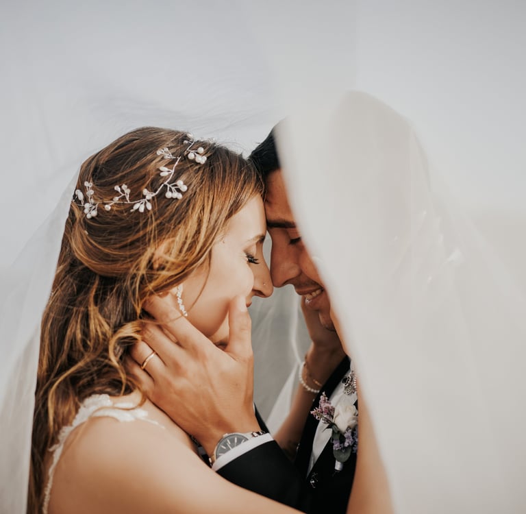 sposo e sposa abbracciati sotto al velo