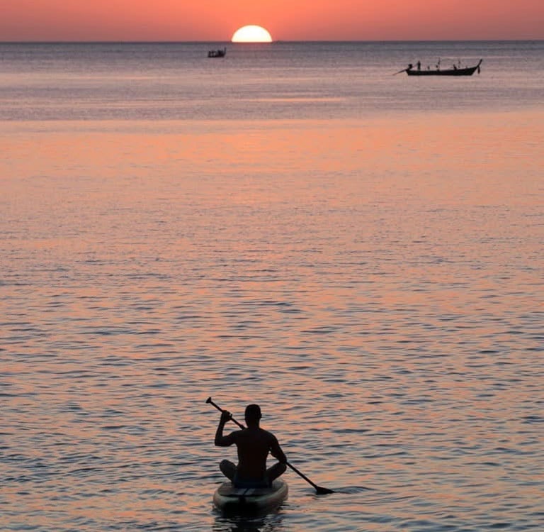 Travel writer Rick Silvia paddles into the sunset by kayak in the bay of Bang Tao