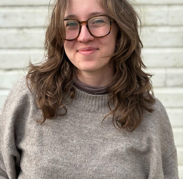 junge Hebamme mit Brille und gewellten Haaren