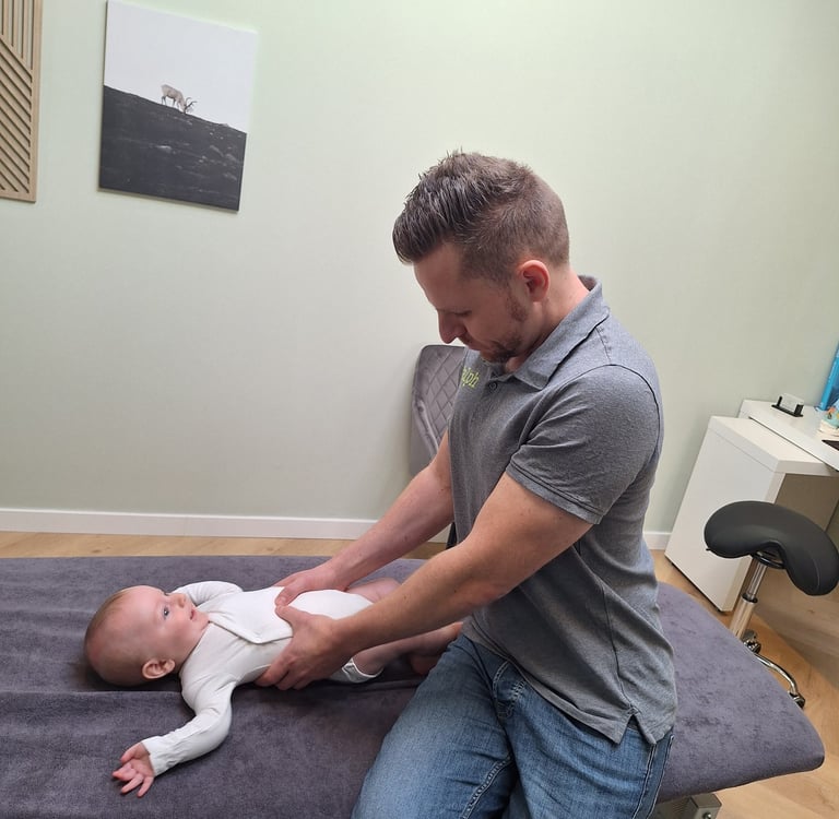 een man geeft een manuele behandeling aan een baby in zijn buik