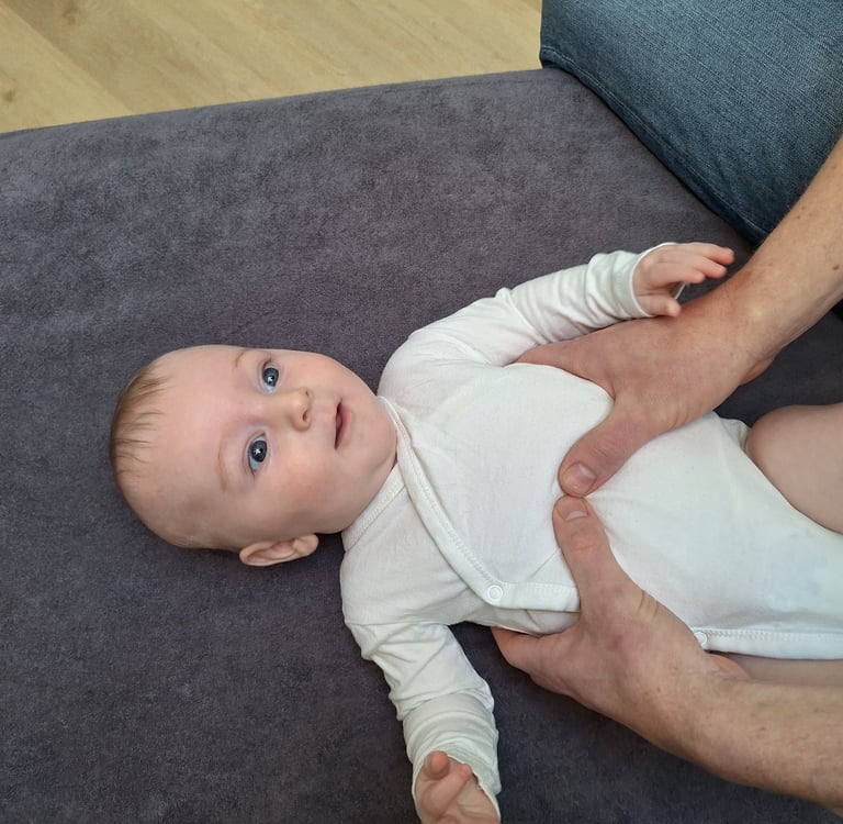 een baby ligt op een tafel met 2 handen van een man