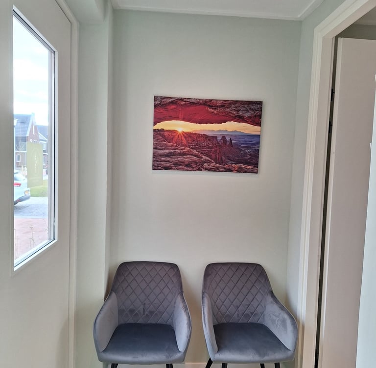 2 stoelen in een kamer met een schilderij aan de muur