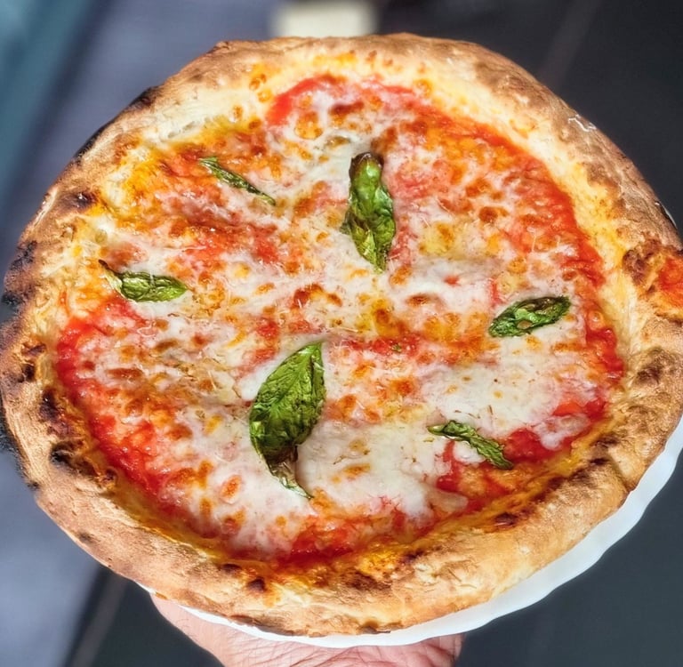 Neapolitan Margherita pizza with melted mozzarella cheese, tomato sauce, and fresh basil on a charred crust.