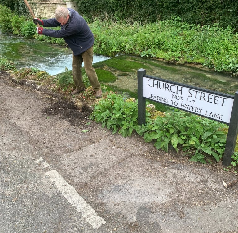 The Chairman of the River Wey Society clearing years of accumulated soil next to the wall 