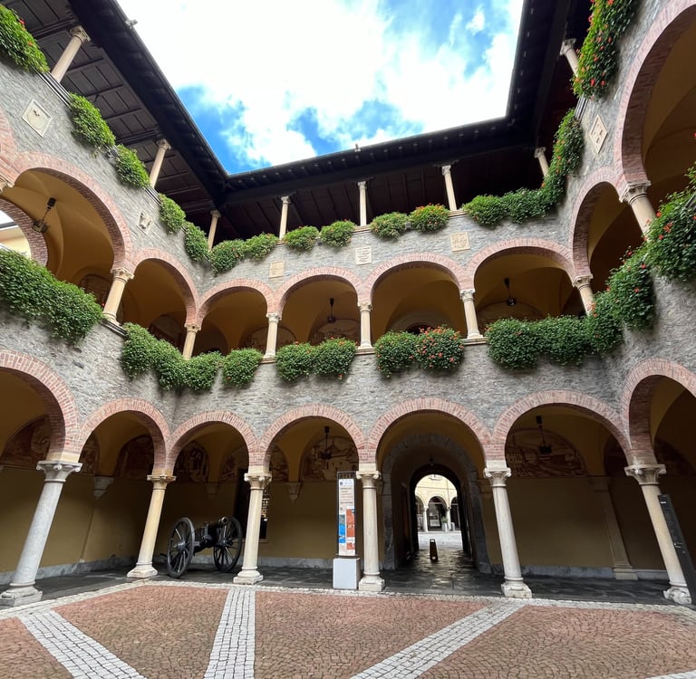 The internal courtyard of the Civic Palace in Bellinzona with lots of arches and flowers