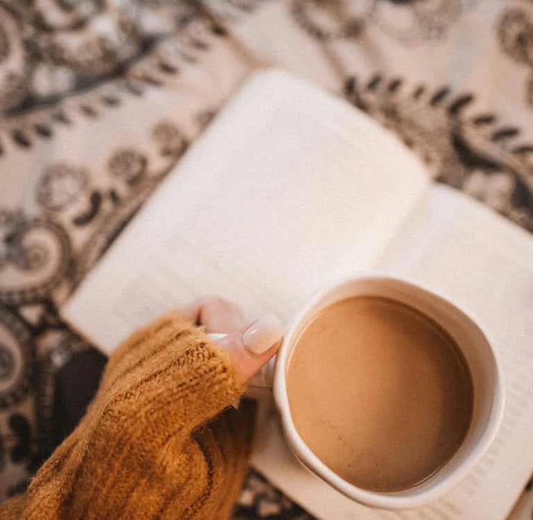 Main de femme tenant une tasse de café sur un livre, symbole d’ancrage doux et d’exploration intérie